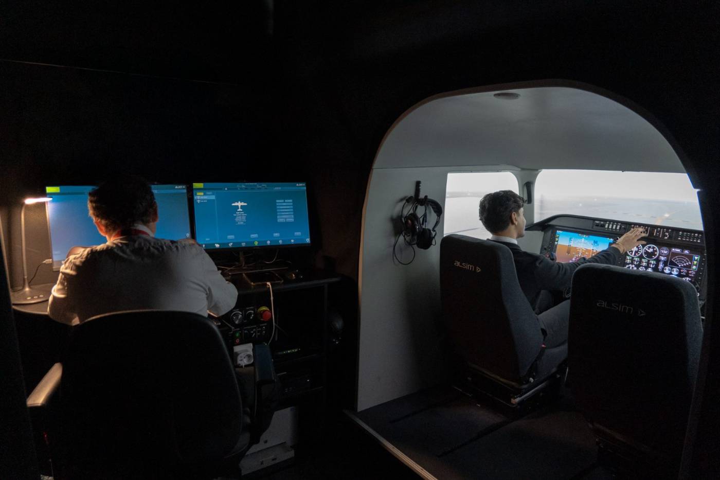 Instructeur au pupitre du simulateur ALSIM AL250 pendant qu'un élève pilote la séance
